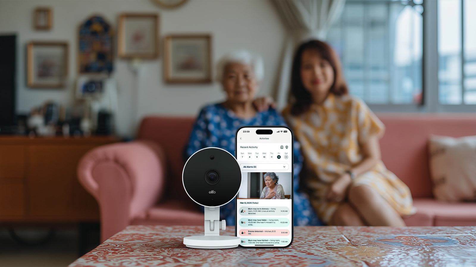 An ELLO camera on a table, with a mother and daughter sitting on a sofa behind it